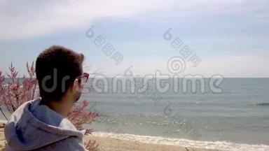 在希腊的哈尔<strong>基迪基</strong>，年轻人看着大海，用手机在沙滩上聊天